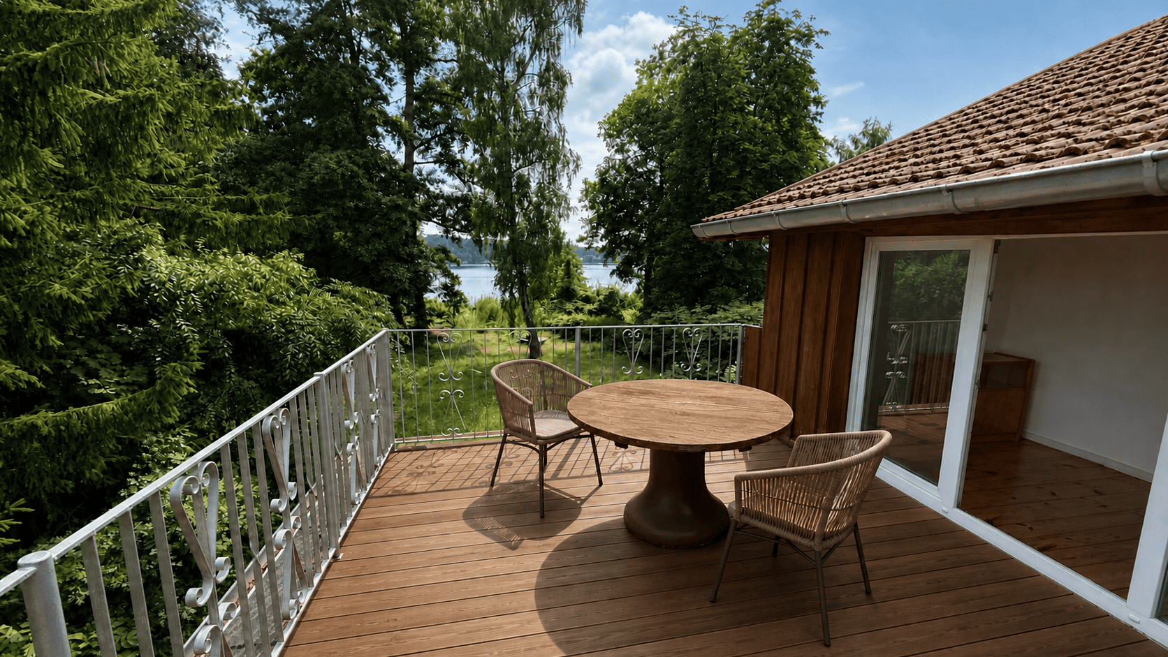 Terrasse am Seeufer mit massivem Holztisch und zwei Stühlen