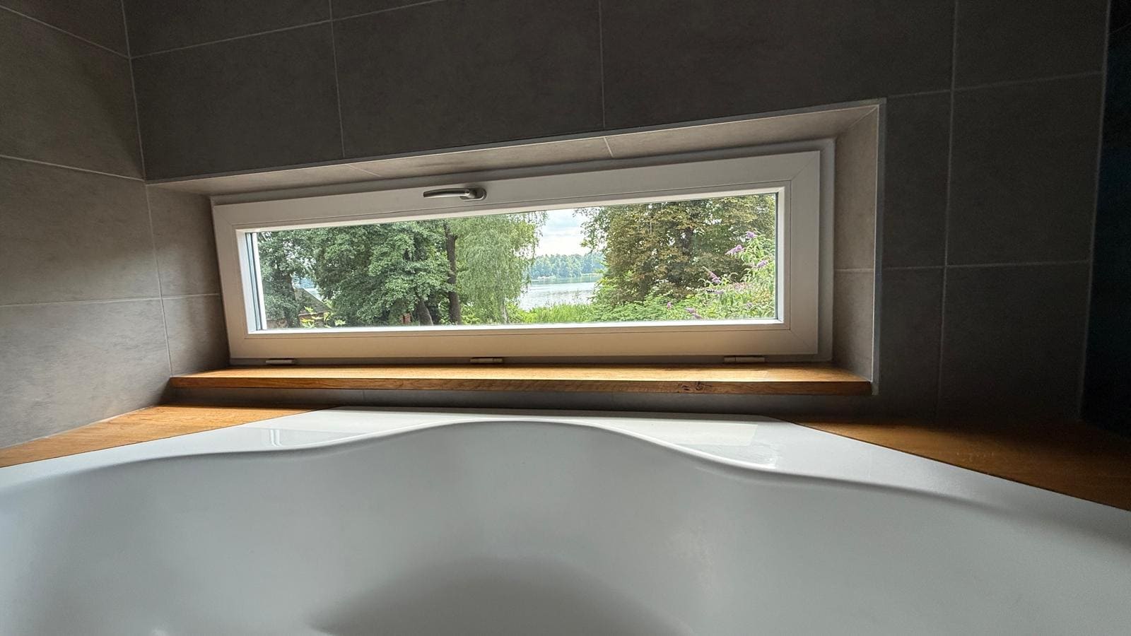 Badewanne mit Panoramafenster und Blick auf den See